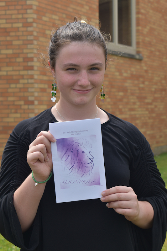 Celia holding a program brochure featuring her lion artwork